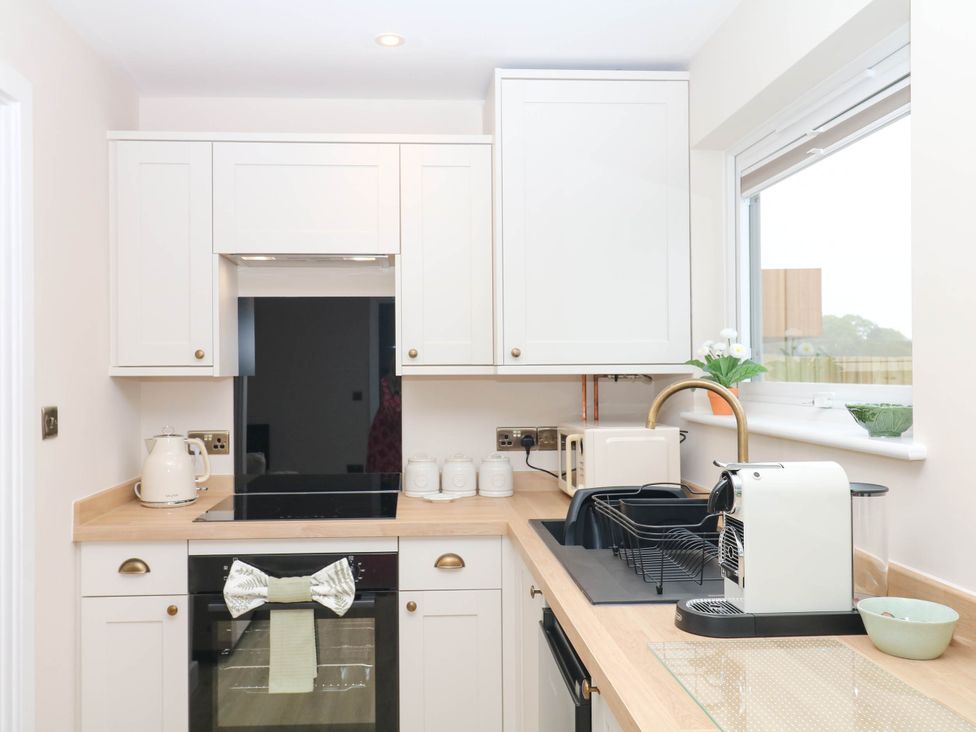 A kitchen with white cabinets and appliances at Little Folley in Whitestone near Tedburn St Mary