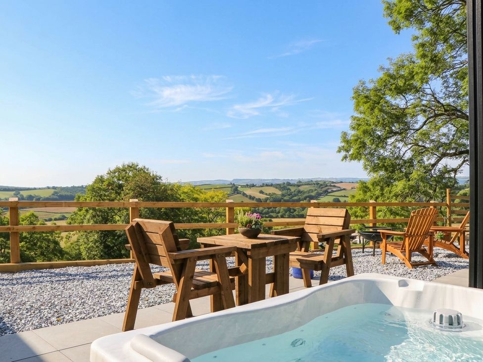 An outdoor area with a hot tub and wooden furniture at Little Folley in Whitestone near Tedburn St Mary