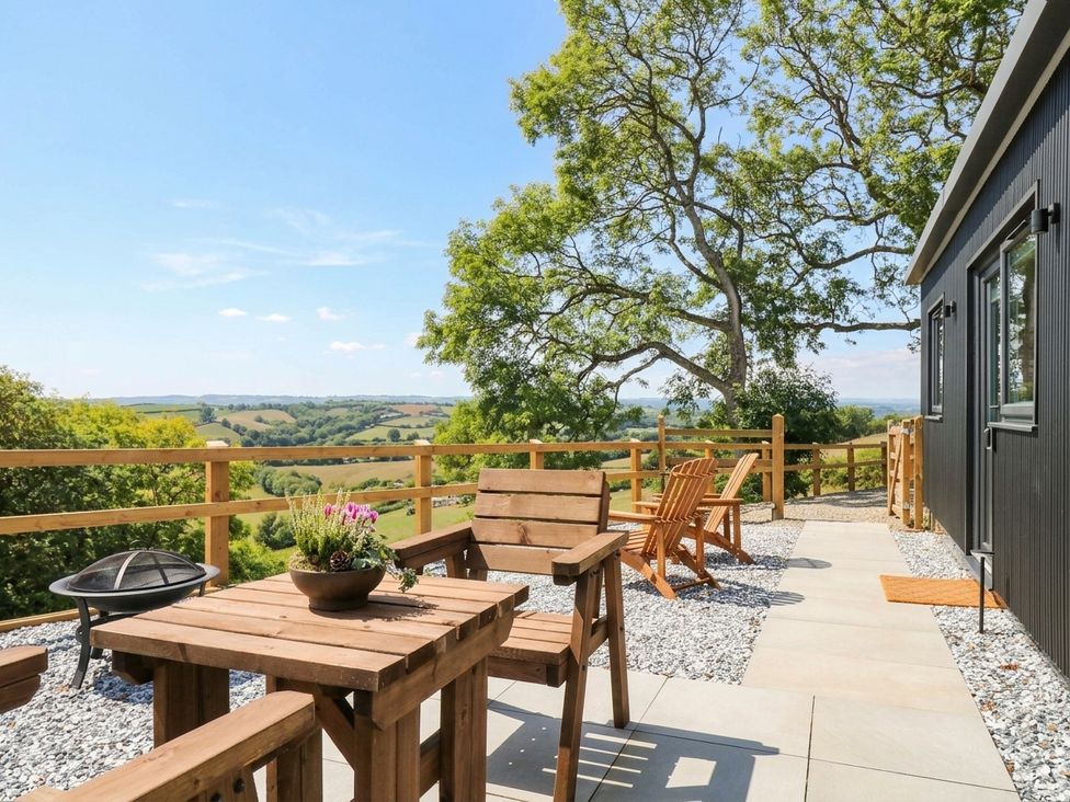 An outdoor space with wooden furniture and a fire pit at Little Folley in Whitestone near Tedburn St Mary