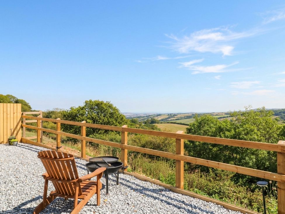 An outdoor area with chairs and table overlooking the countryside at Little Folley in Whitestone near Tedburn St Mary