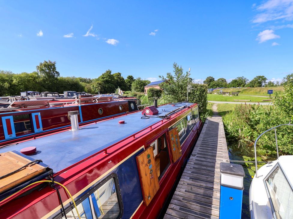 Houseboats moored along a canal with a clear blue sky at Escape II Oakwood Marina