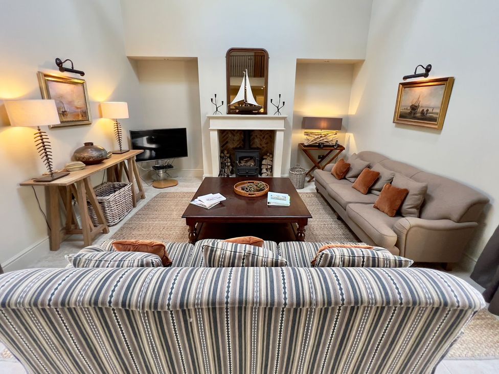 A living room with a sofa, coffee table, and lamp at The Chimney in Bamburgh