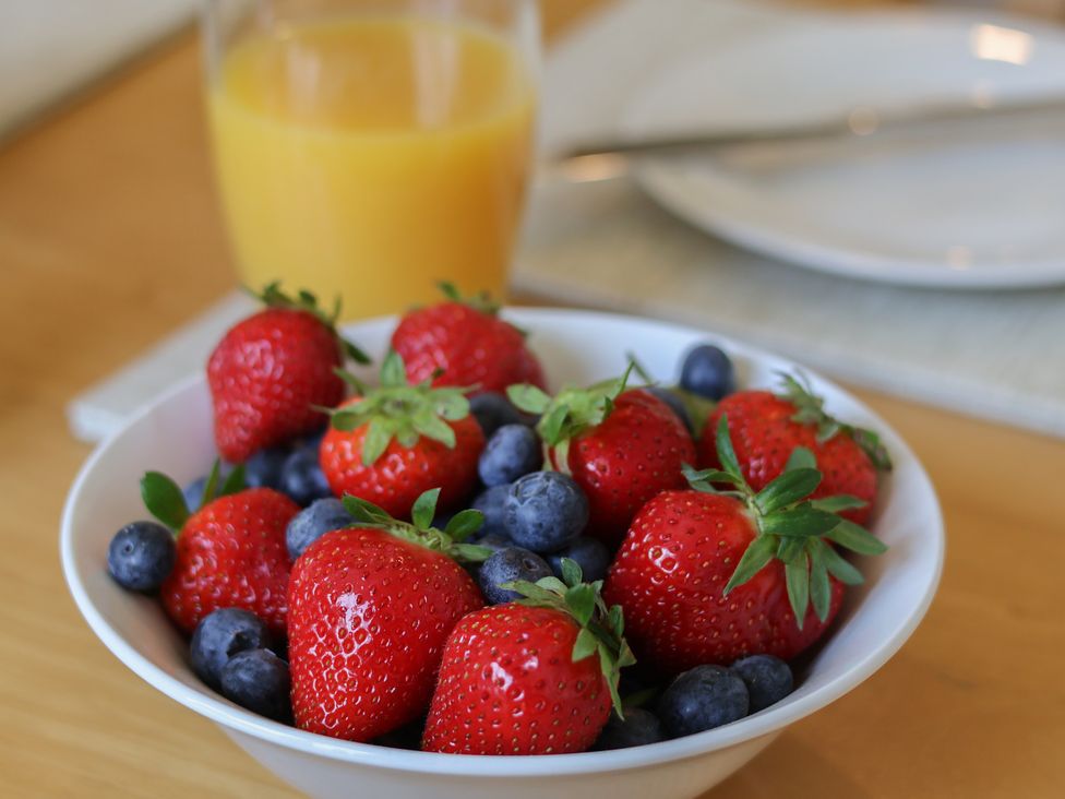 A bowl of strawberries and blueberries with juice at Helmsley Cottage in Helmsley