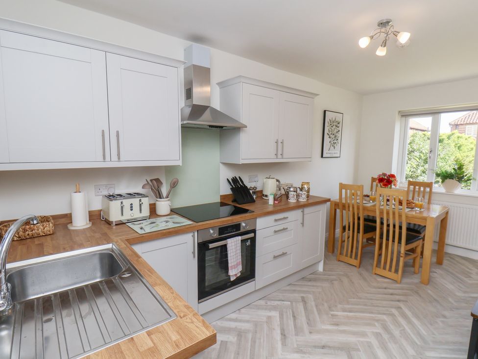 A kitchen with cabinets and dining area at Helmsley Cottage in Helmsley