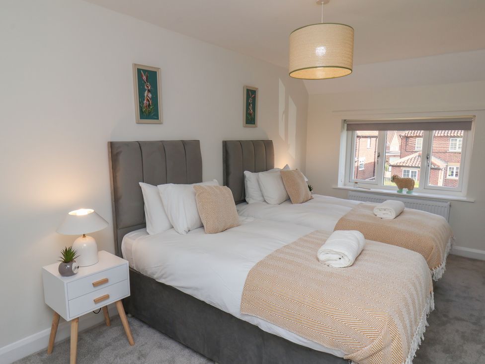 A bedroom with two beds and a window at Helmsley Cottage in Helmsley
