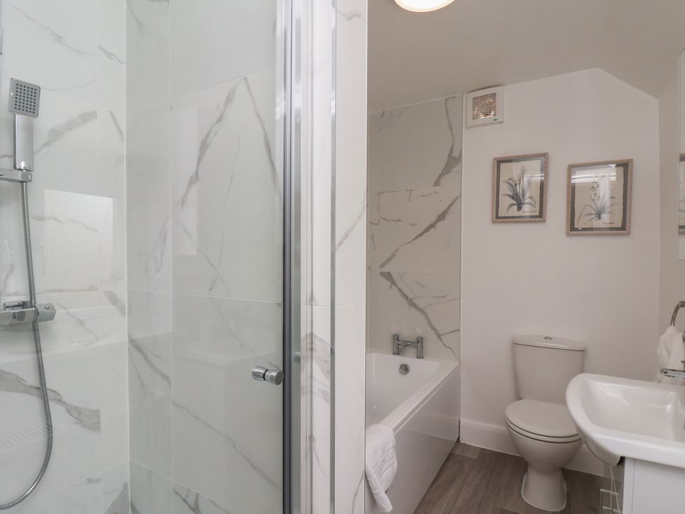 A bathroom with a shower, bathtub, and sink at Helmsley Cottage in Helmsley