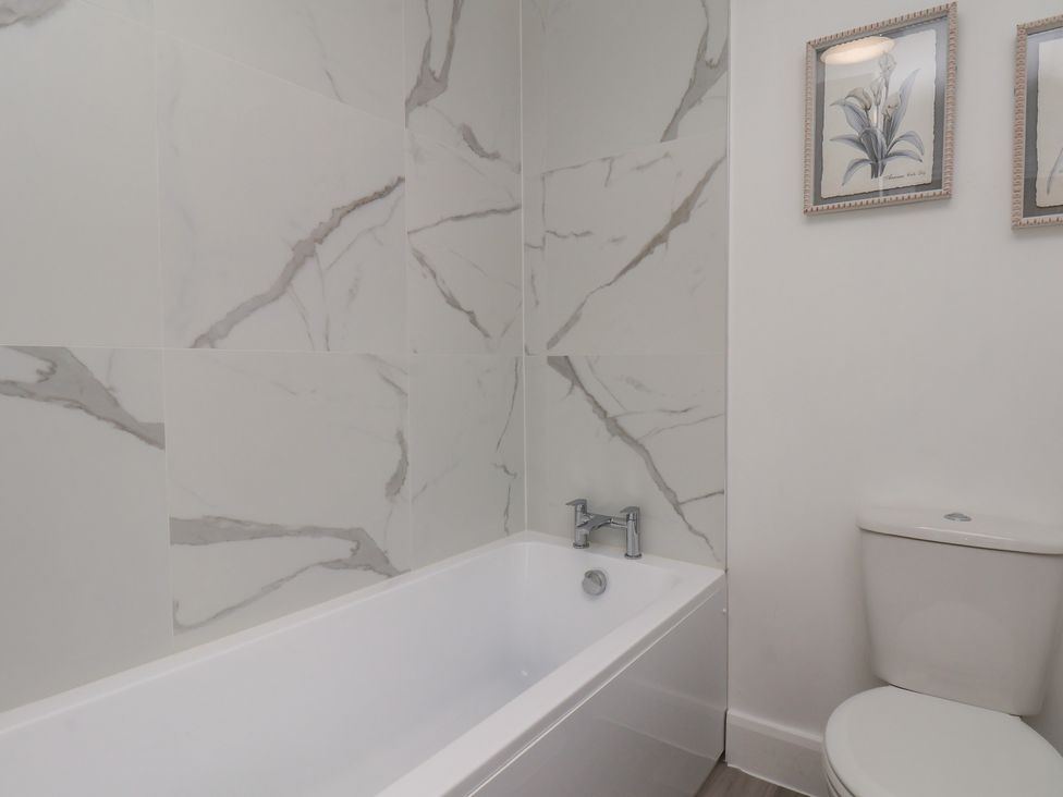 A bathroom with a bathtub and toilet at Helmsley Cottage in Helmsley
