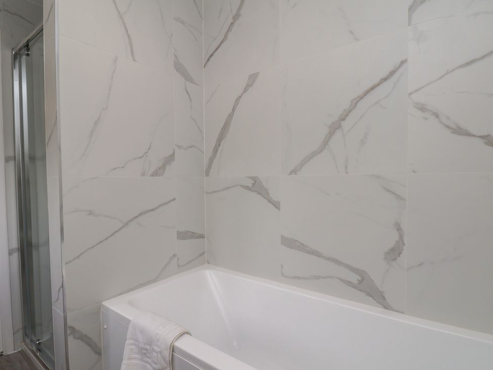 A bathroom with a bathtub and shower enclosure at Helmsley Cottage in Helmsley