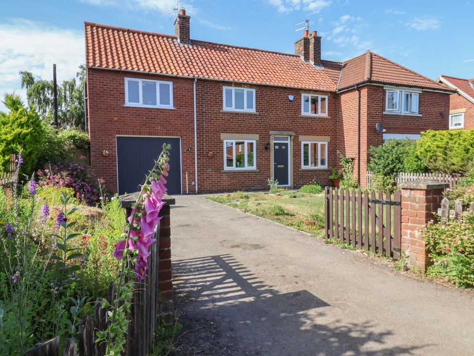 A house with a garage and flowers in the front yard at Helmsley Cottage Helmsley