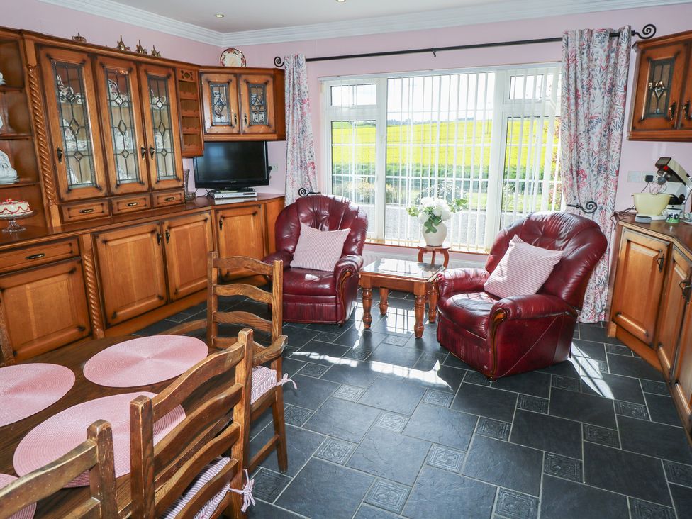 A kitchen with wooden cabinets and red armchairs at Marie's Country Home, Ardee, County Louth