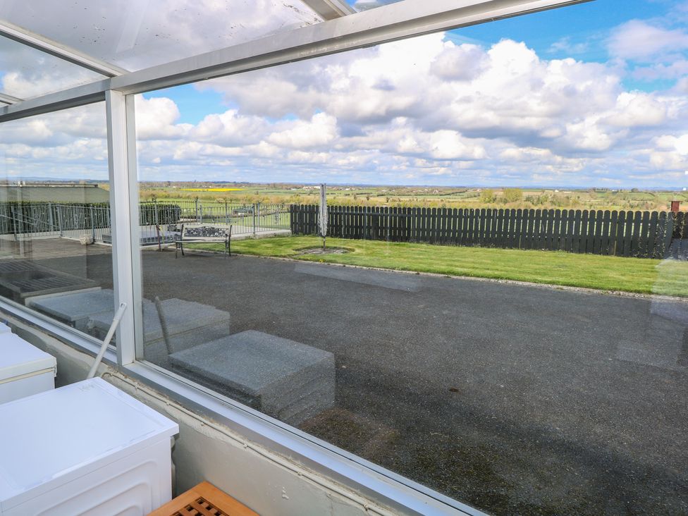 A view from a conservatory showing a grassy area and a wooden fence at Marie's Country Home in Ardee, County Louth