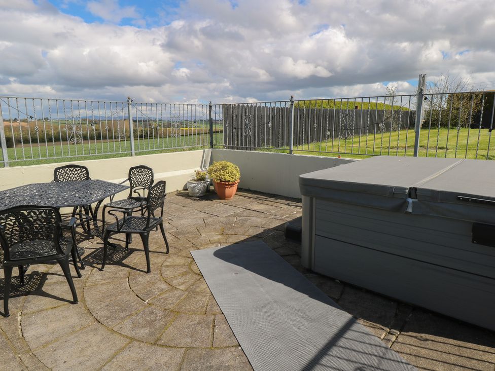 An outdoor area with a table, chairs, hot tub, and potted plant at Marie's Country Home in Ardee, County Louth