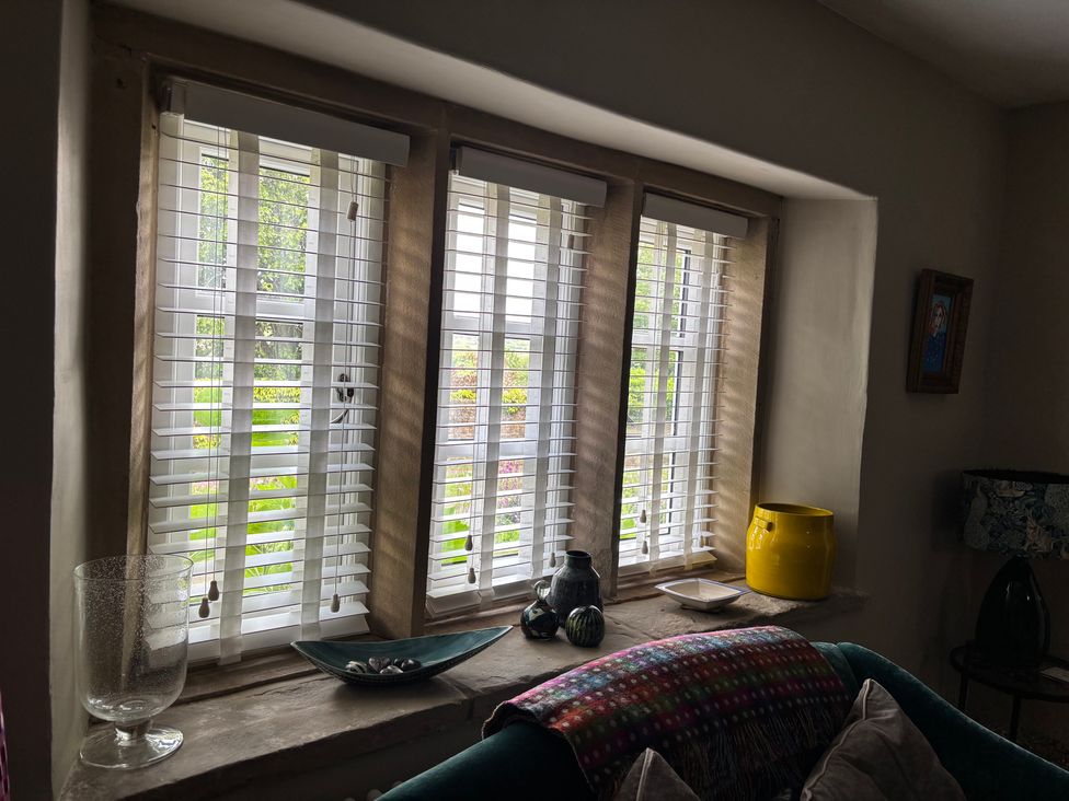 A living room with window blinds and a vase at Holly Cottage in Totley