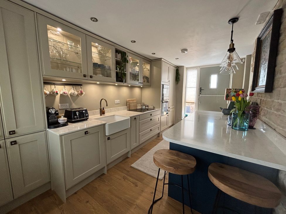 A kitchen with a sink and bar stools at Holly Cottage in Totley