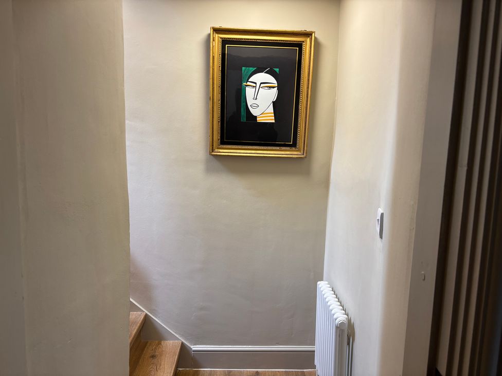 A hallway with stairs and a framed artwork at Holly Cottage in Totley