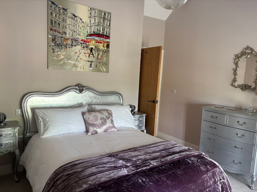 A bedroom with a bed and nightstand at Holly Cottage in Totley
