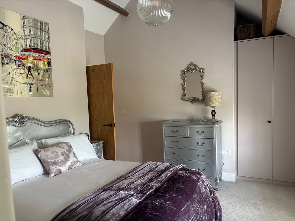 A bedroom with a bed, dresser, and artwork at Holly Cottage in Totley