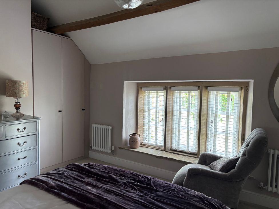 A bedroom with a window, wardrobe, radiator, and chest of drawers at Holly Cottage in Totley