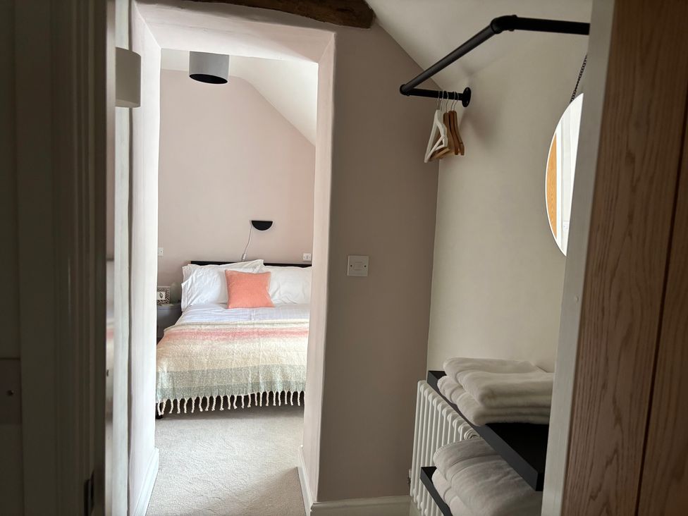 A bedroom with a bed and shelving at Holly Cottage in Totley