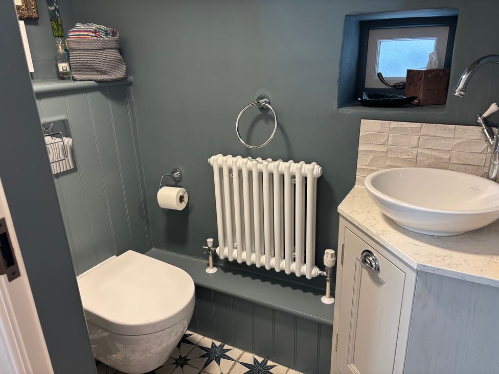 A bathroom with a toilet, sink and radiator at Holly Cottage in Totley