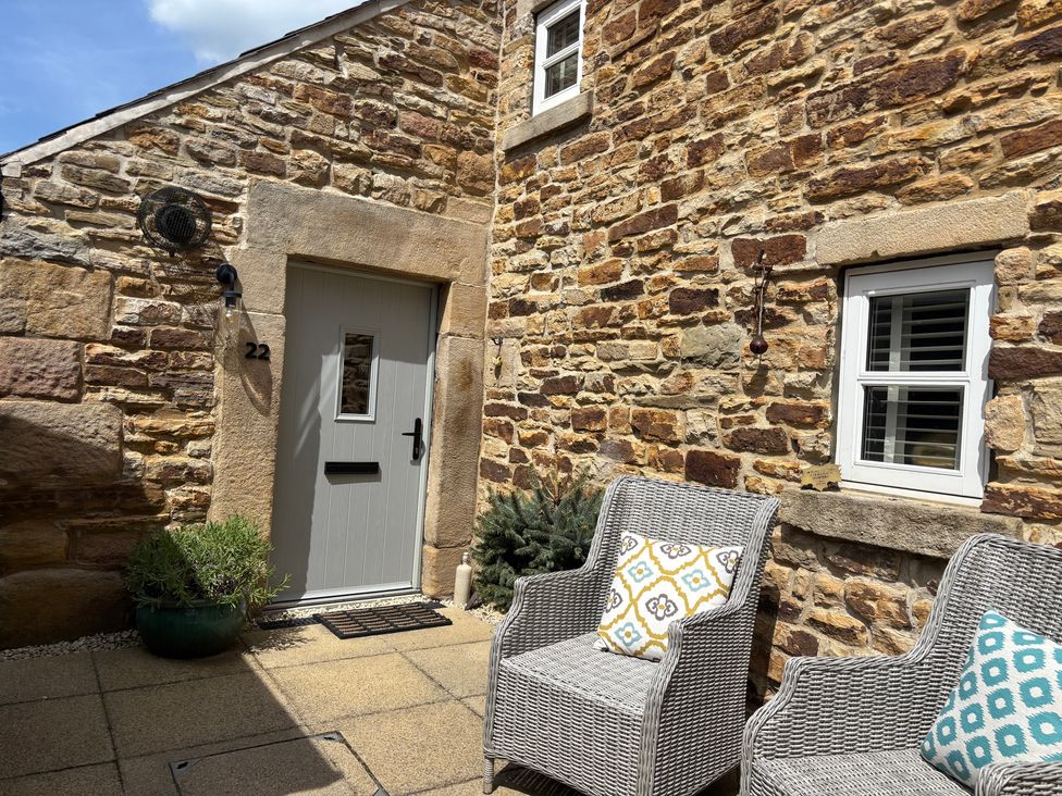 An outdoor patio with seating and stone wall at Holly Cottage in Totley