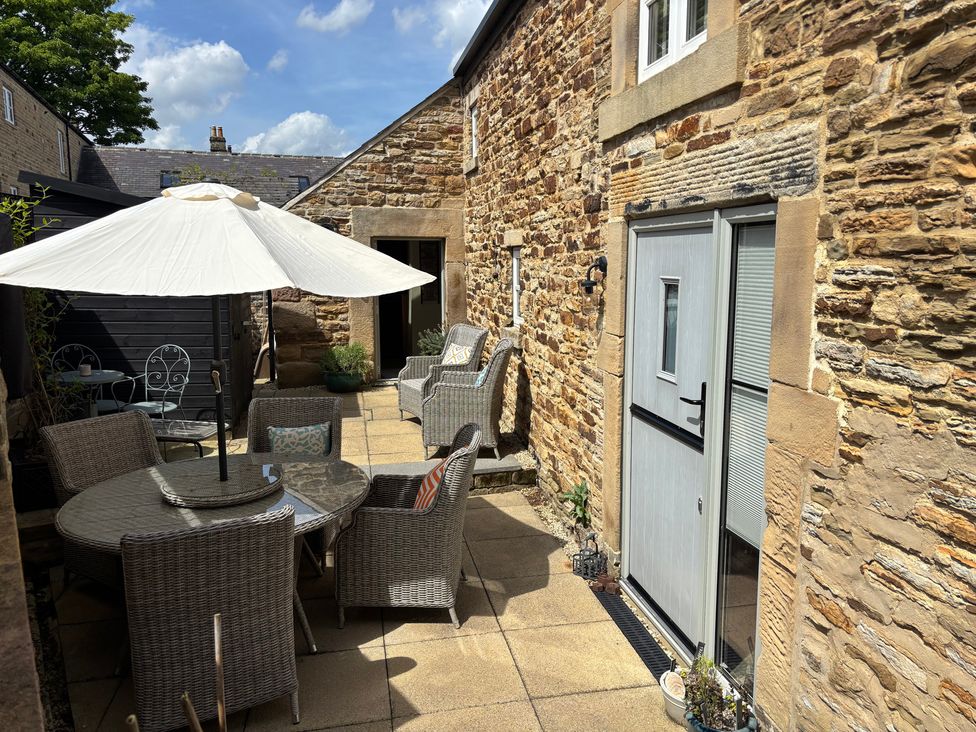 A patio area with seating and an umbrella at Holly Cottage in Totley