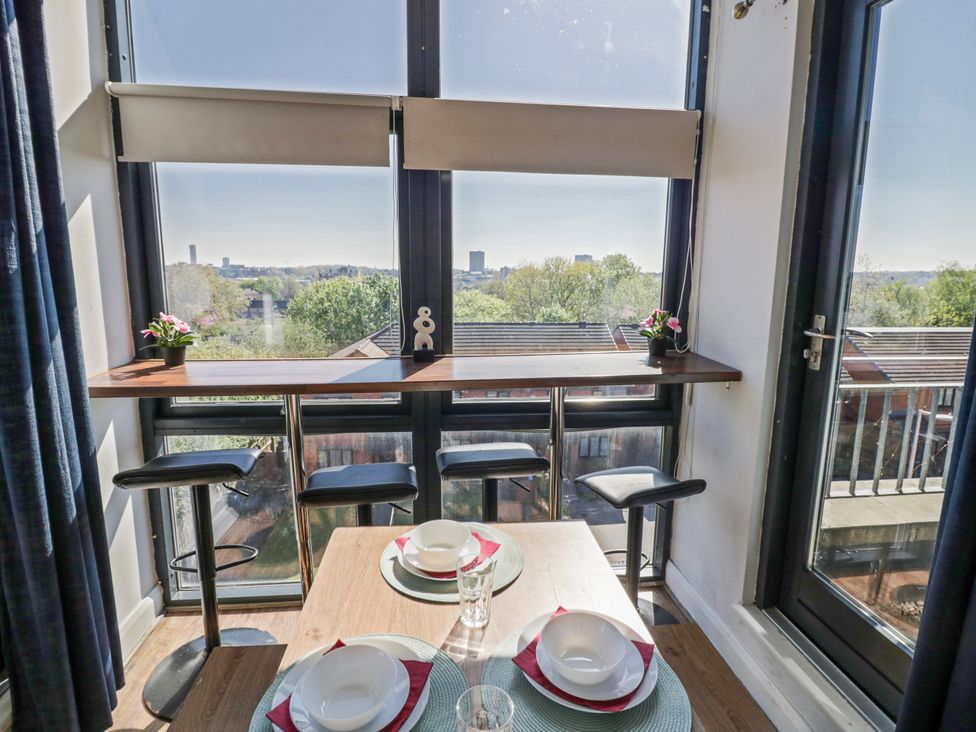 A dining area with a table and two bar stools at Apartment 10 Birmingham