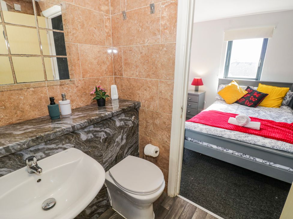 A bathroom with a sink and toilet, leading to a bedroom with a bed at Apartment 10 Birmingham