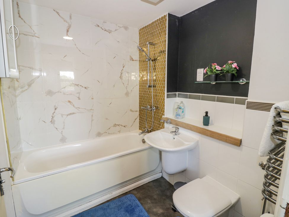 A bathroom with bathtub, shower, washbasin, and towel rail at Apartment 10 in Birmingham