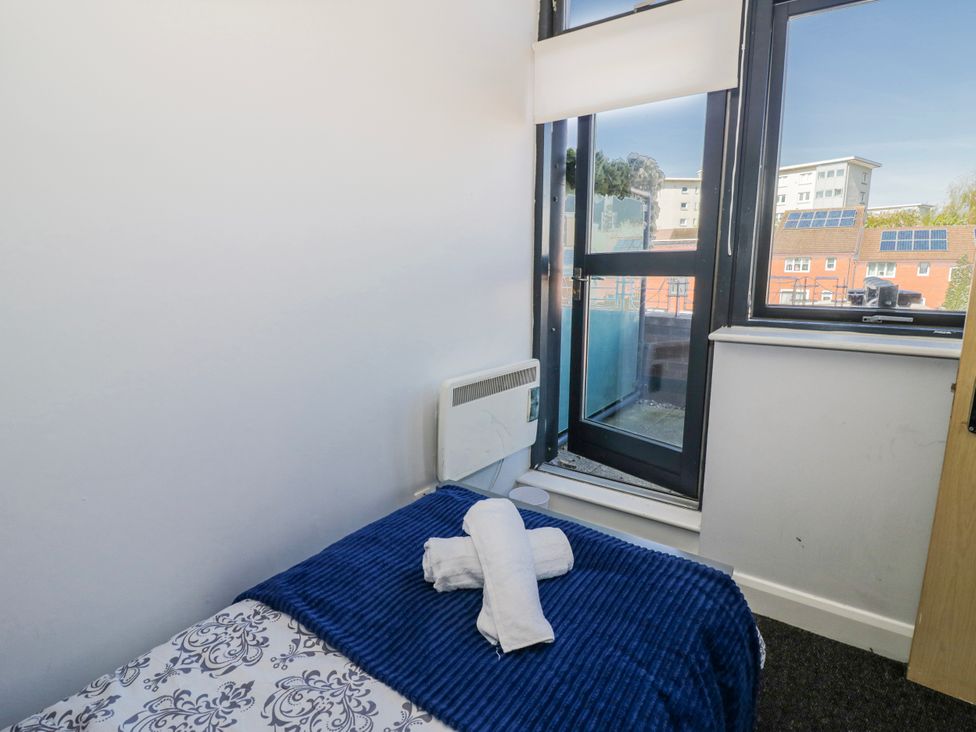 A bedroom with a bed, towels on top, and a window at Apartment 10 Birmingham