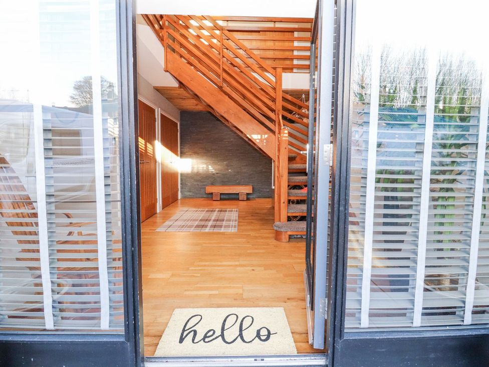 An entrance with a door mat and wooden stairs at The Steading in Dumfries