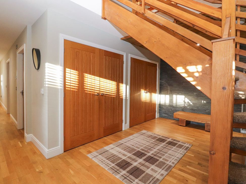 A hallway with wooden stairs and doors at The Steading in Dumfries