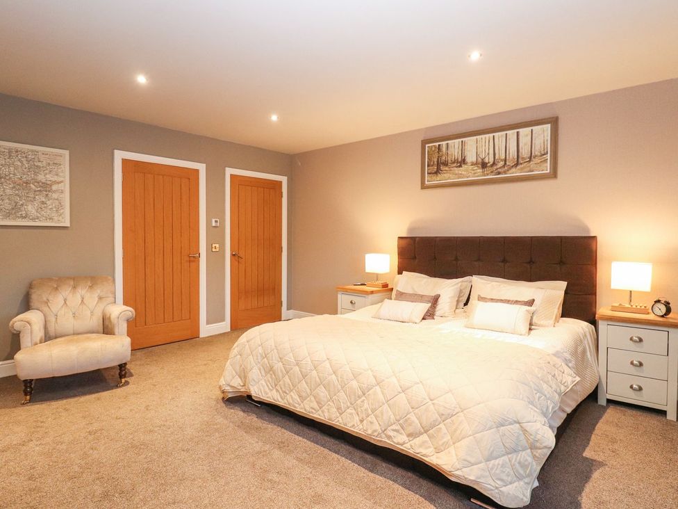 A bedroom with a bed and chair at The Steading in Dumfries