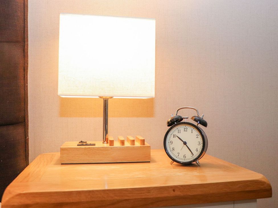 A lamp and alarm clock on a nightstand at The Steading in Dumfries