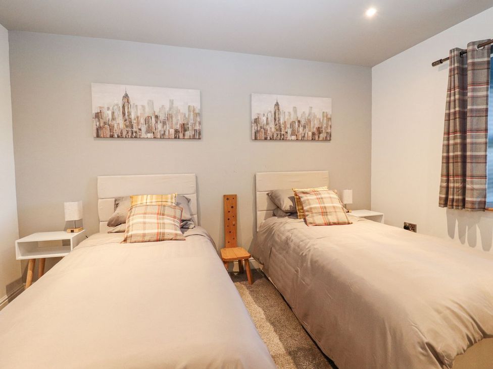 A bedroom with two single beds and wall art at The Steading in Dumfries