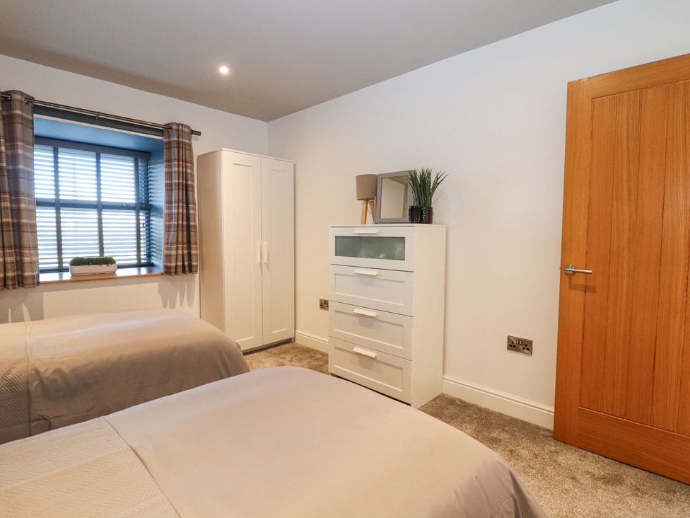 A bedroom with two beds and a wardrobe at The Steading in Dumfries
