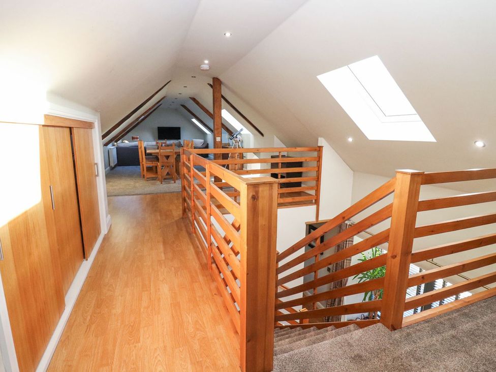 A hallway with a staircase and dining area at The Steading in Dumfries