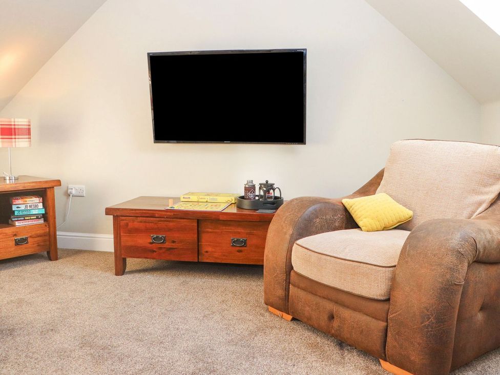 A living room with a television and armchair at The Steading in Dumfries