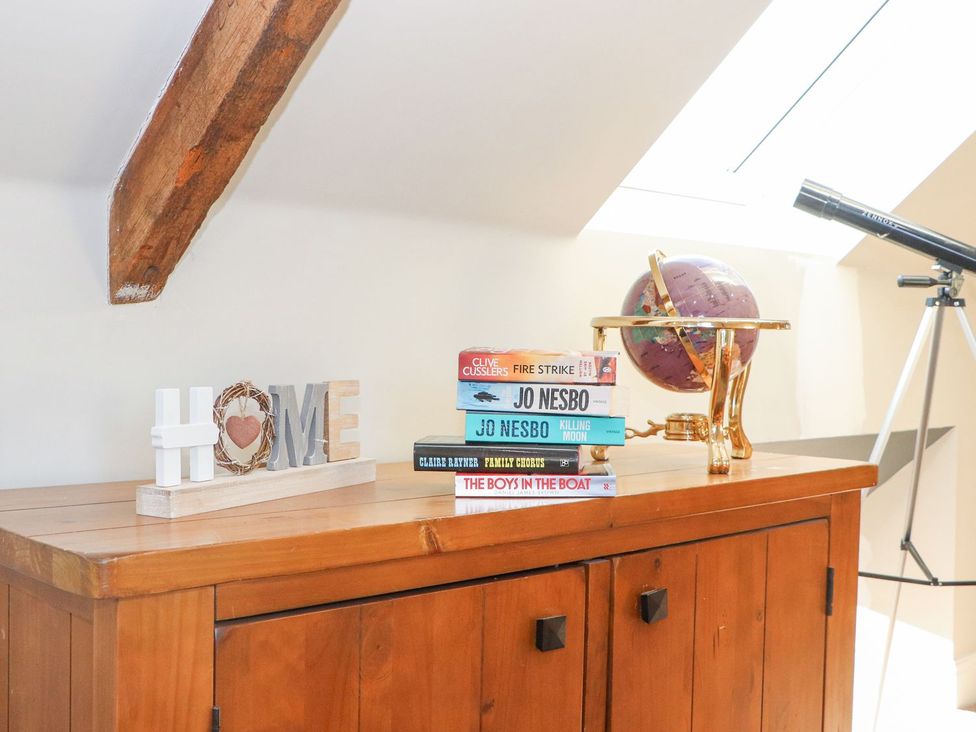 A living room with a bookshelf and telescope at The Steading in Dumfries