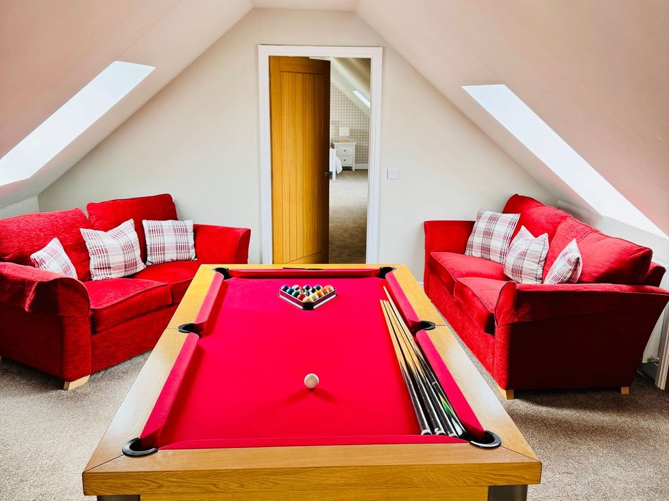 A snug with a pool table and red sofas at The Steading in Dumfries