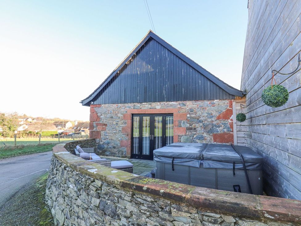 An outdoor area with a hot tub and stone wall at The Steading in Dumfries