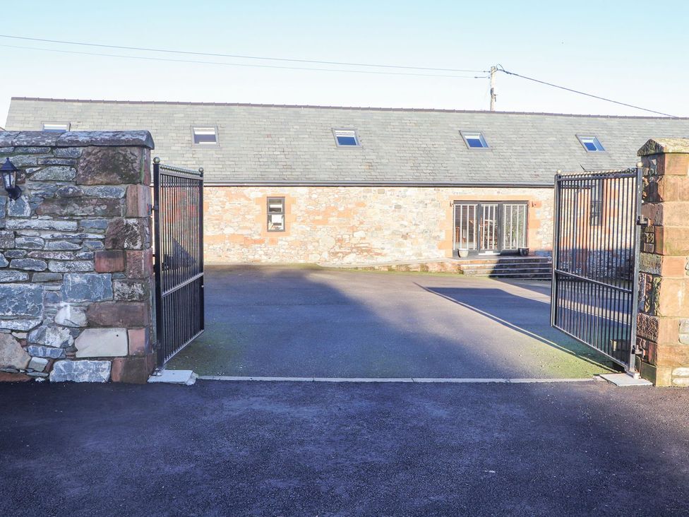 An outdoor view of a gated entrance with a stone wall and a building at The Steading in Dumfries