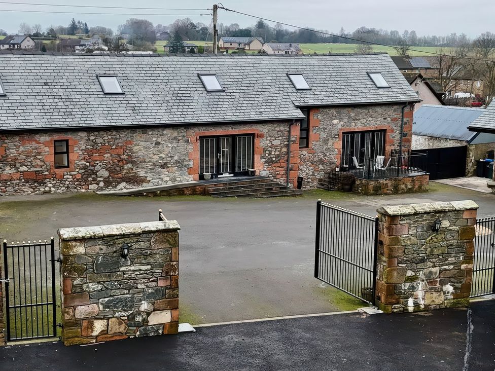 A building with a stone wall and gate at The Steading in Dumfries