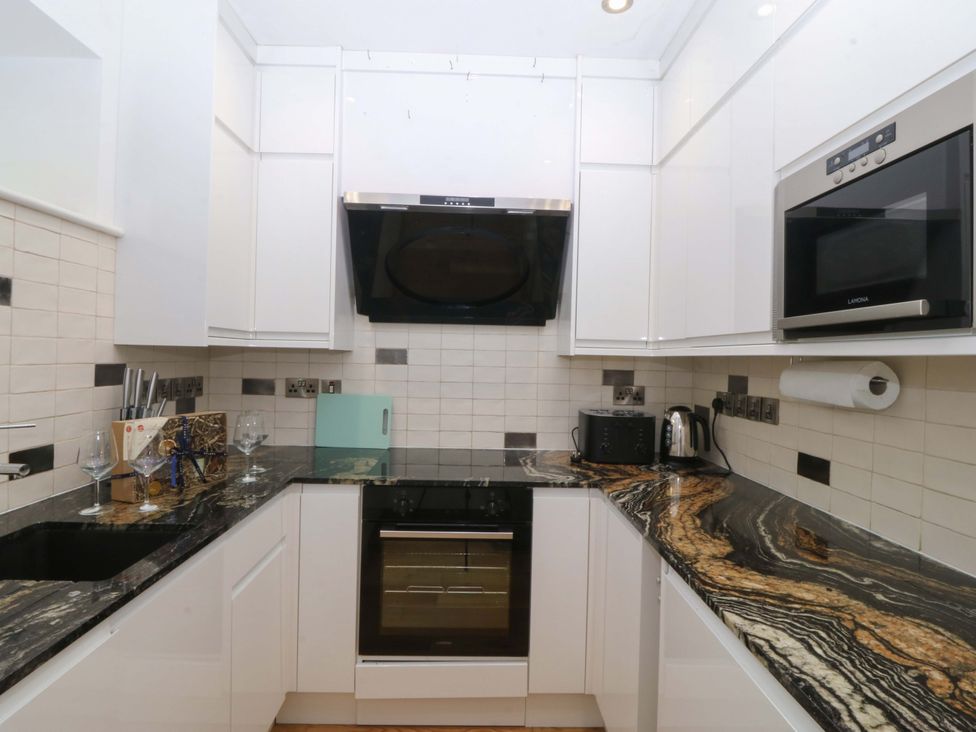A kitchen with cabinets and appliances at Apartment 1, Bryn Mel Manor in Menai Bridge