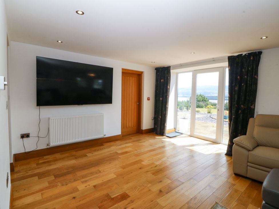 A living room with a television and a door to the outside at Apartment 1, Bryn Mel Manor Menai Bridge