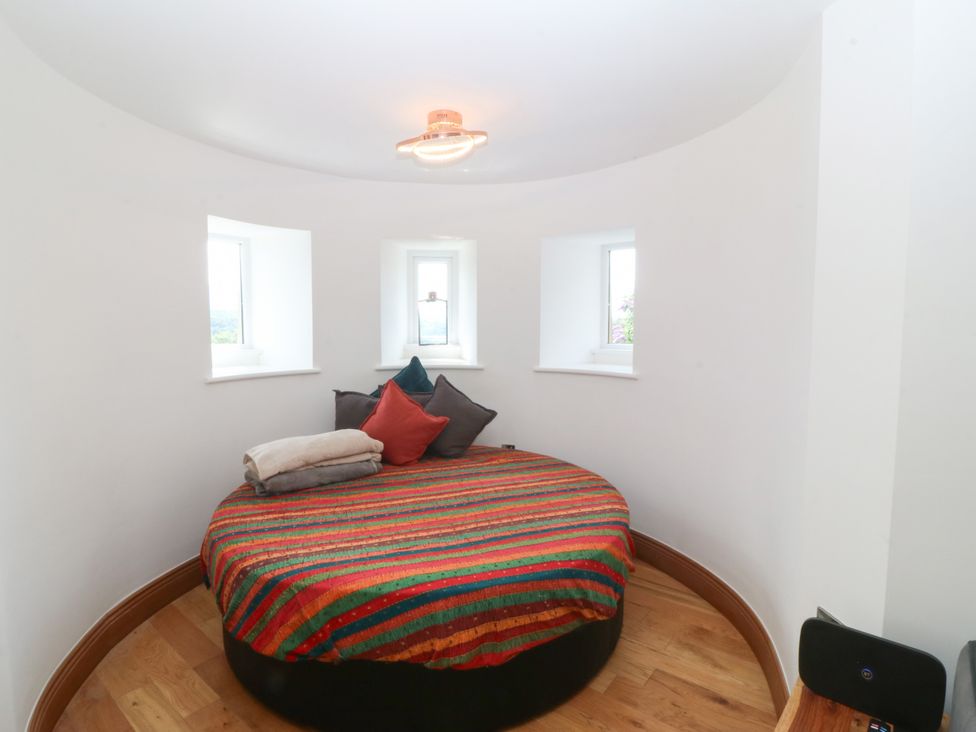 A bedroom with a round bed and windows at Apartment 1, Bryn Mel Manor Menai Bridge