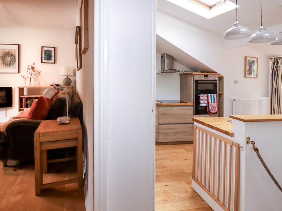 A living room with a sofa and kitchen area at Dolphin Cottage in Falmouth