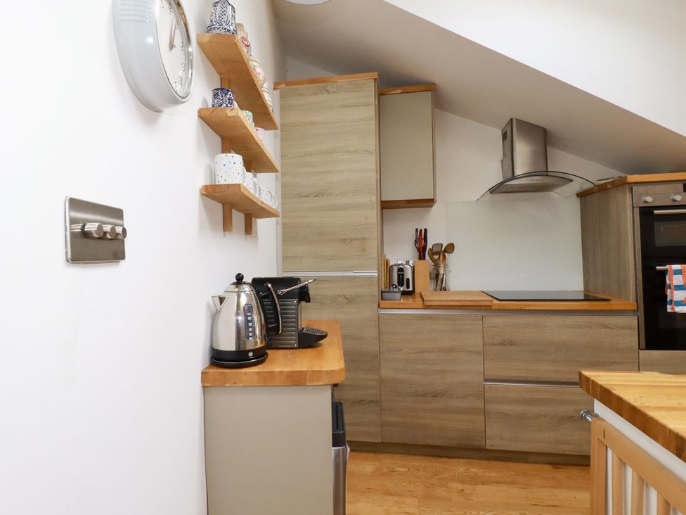 A kitchen with cabinets, a kettle, and utensils at Dolphin Cottage in Falmouth