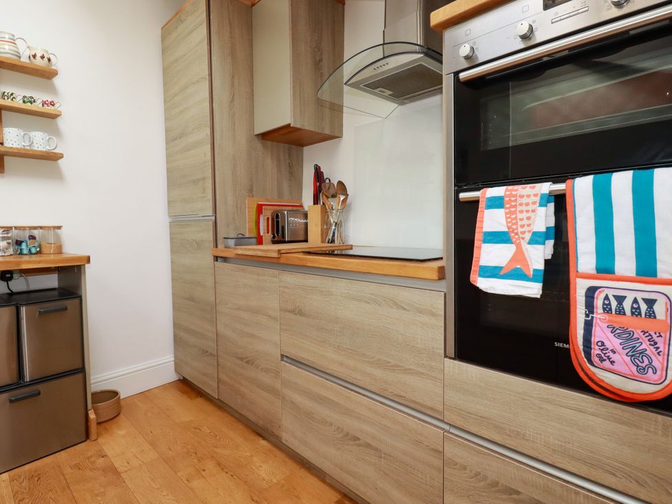A kitchen with cabinets and appliances at Dolphin Cottage in Falmouth