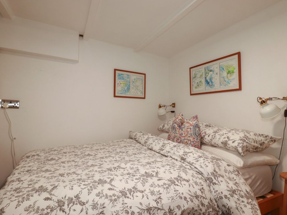 A bedroom with a bed and wall art at Dolphin Cottage in Falmouth